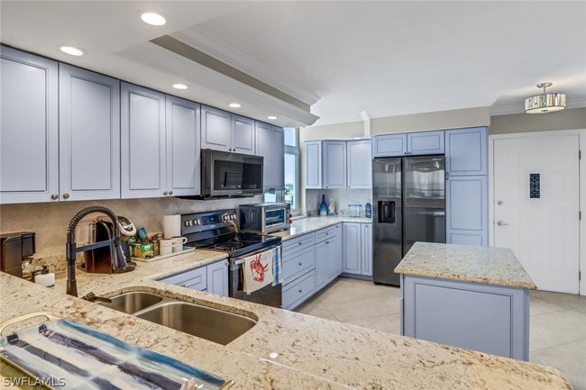 Kitchen featuring light tile patterned flooring, backsplash, crown molding, and appliances with stainless steel finishes | Image 10