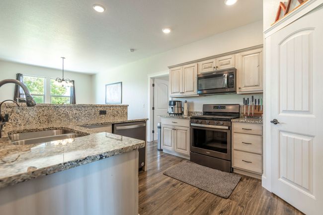 Kitchen featuring appliances with stainless steel finishes, dark wood-type flooring, recessed lighting, light stone countertops, and pendant lighting | Image 9