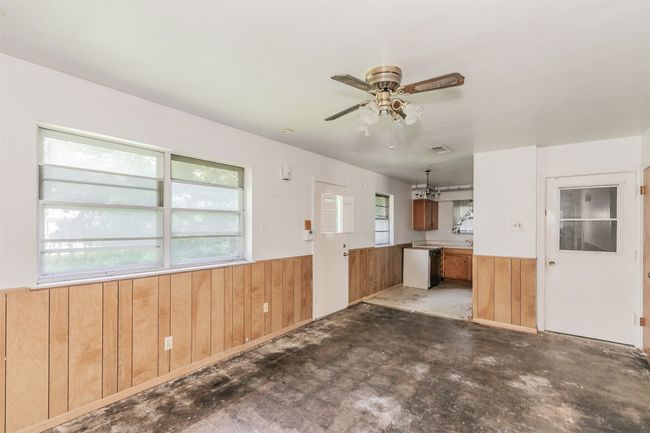 Kitchen with a wainscoted wall, wood walls, ceiling fan, dishwasher, and concrete floors | Image 17
