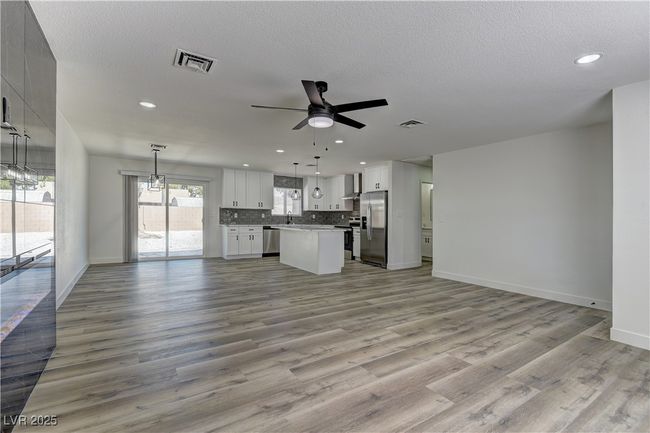 Unfurnished living room with ceiling fan, recessed lighting, baseboards, wood finished floors, and a textured ceiling | Image 8