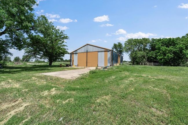 View of green lawn with a pole building, concrete driveway, a detached garage, and an outdoor structure | Image 40