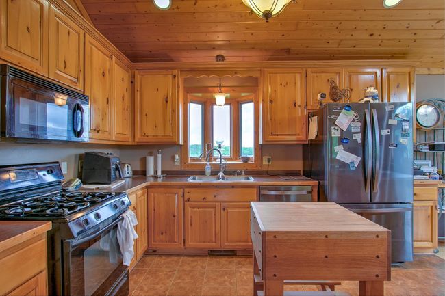 Pine kitchen cabinets, ceramic floor, and bay window. | Image 12