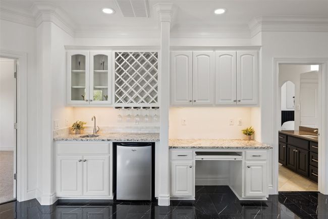Kitchen featuring a sink, white cabinets, glass insert cabinets, light stone countertops, and crown molding | Image 25
