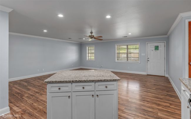 Kitchen with open floor plan, a ceiling fan, ornamental molding, and dark wood-style flooring | Image 6