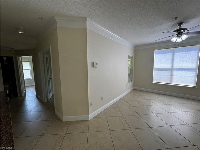 Unfurnished room with ceiling fan, baseboards, a textured ceiling, light tile patterned flooring, and crown molding | Image 11