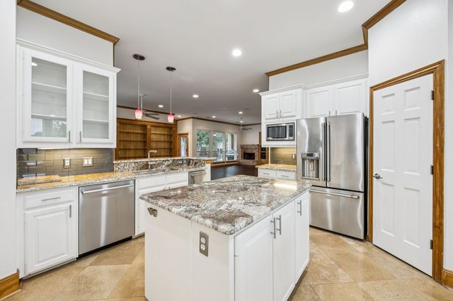 Kitchen featuring granite countertops, stainless steel appliances, an island, recessed lighting, and decorative backsplash | Image 11