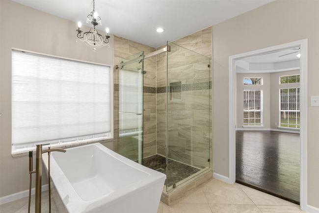 Full bathroom with a freestanding tub, an inviting chandelier, baseboards, tile patterned floors, and a stall shower | Image 26