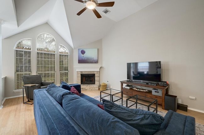 Family Room area with a ceiling fan, wood finished floors, a fireplace, lofted ceiling, and baseboards | Image 19
