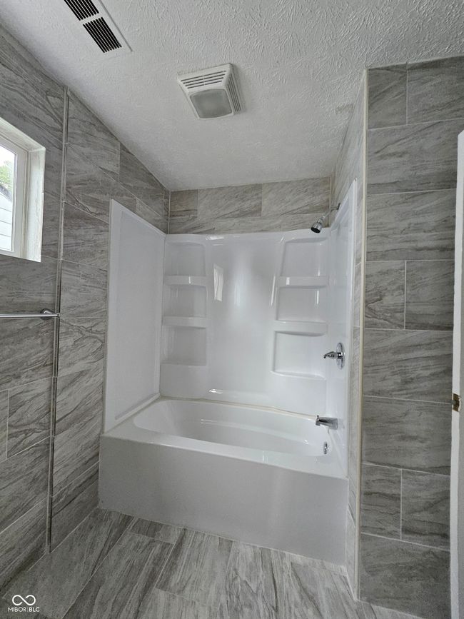 bathroom with shower / tub combination and a textured ceiling | Image 6