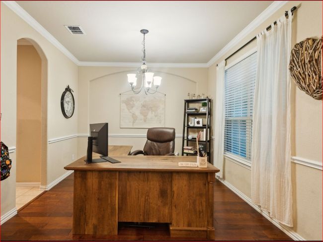 Office area with dark wood finished floors, ornamental molding, a chandelier, and arched walkways | Image 6