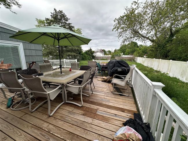 Wooden deck with outdoor dining space and a fenced backyard | Image 12