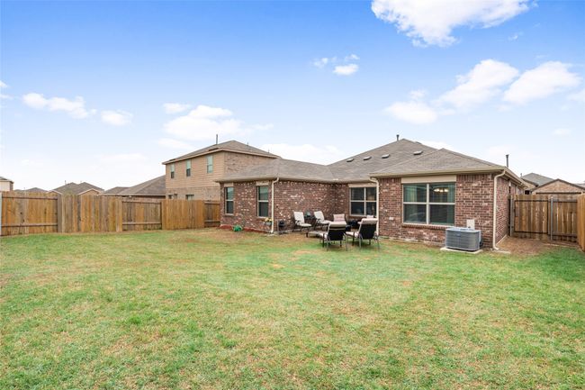 Back of house featuring a fenced backyard, a lawn, central air condition unit, and brick siding | Image 29