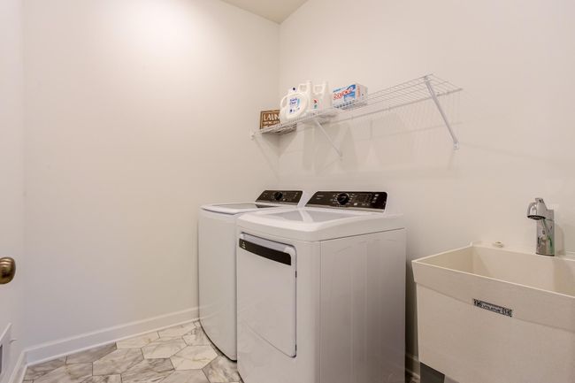 Dedicated laundry space with modern washer/dryer set, utility sink, and convenient overhead storage. | Image 30