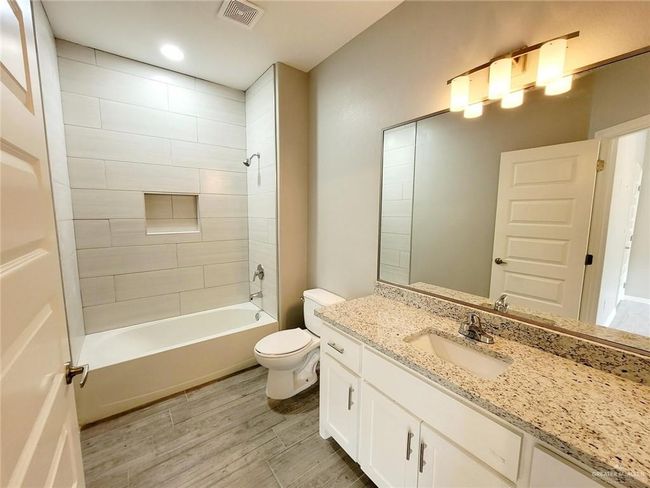 Bathroom featuring wood finished floors, visible vents, toilet, vanity, and shower / bathing tub combination | Image 16