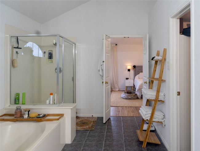 Ensuite bathroom featuring a stall shower, a bath, tile patterned flooring, and lofted ceiling | Image 34
