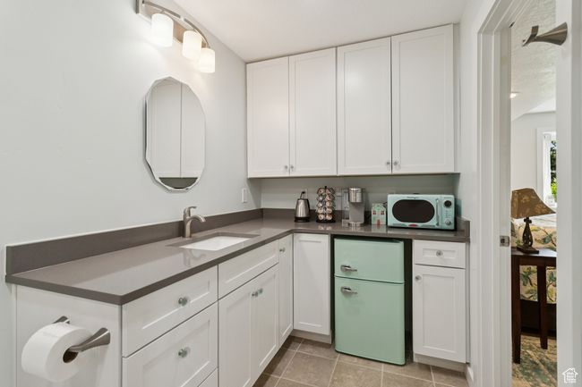 Kitchen with white appliances, white cabinetry, dark countertops, and light tile patterned floors | Image 33