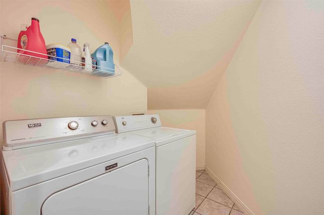 Laundry area with light tile patterned flooring, baseboards, laundry area, and washer and clothes dryer | Image 23