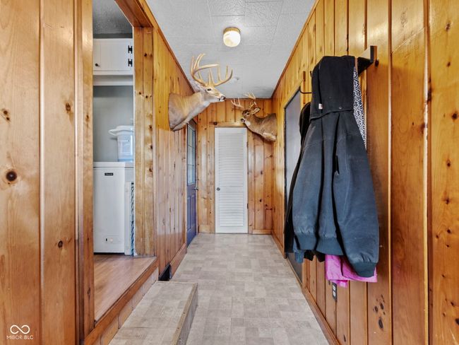 mudroom with light floors, wooden walls, and a textured ceiling | Image 15