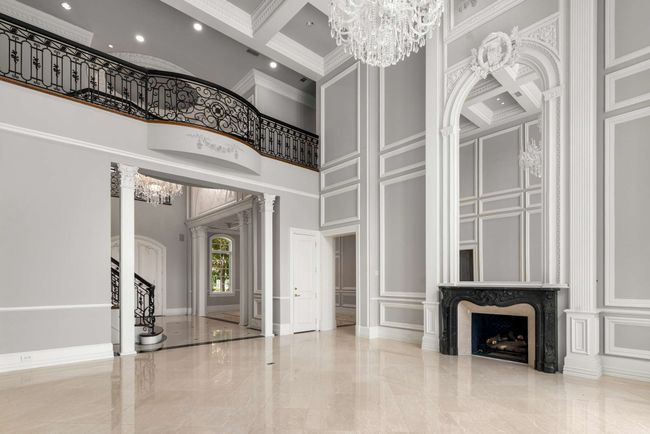 Formal living area with decorative wall, a towering ceiling, marble tiled floors, a chandelier, and crown molding | Image 6
