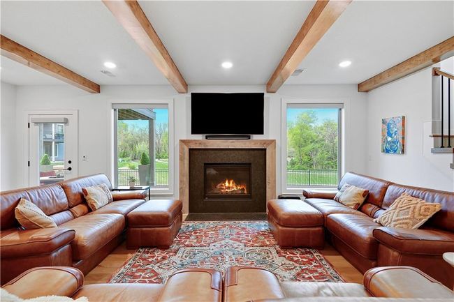 Living room featuring plenty of natural light, a glass covered fireplace, beamed ceiling, and light wood-style flooring | Image 41