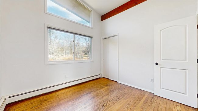 Unfurnished bedroom with beam ceiling, light wood-style floors, a closet, and a baseboard radiator | Image 20