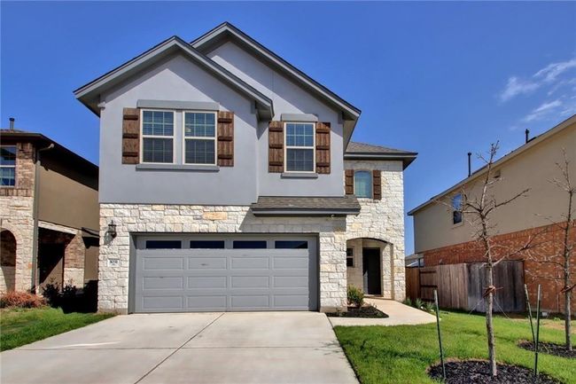 View of front of house with stone siding, driveway, an attached garage, stucco siding, and a shingled roof | Image 37