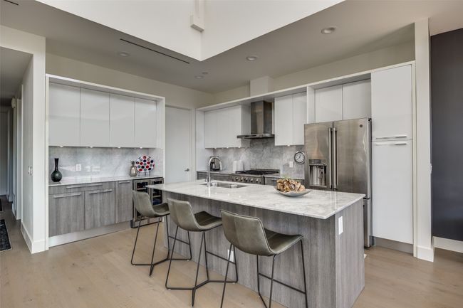 Kitchen with modern cabinets, high end refrigerator, and wall chimney range hood | Image 10