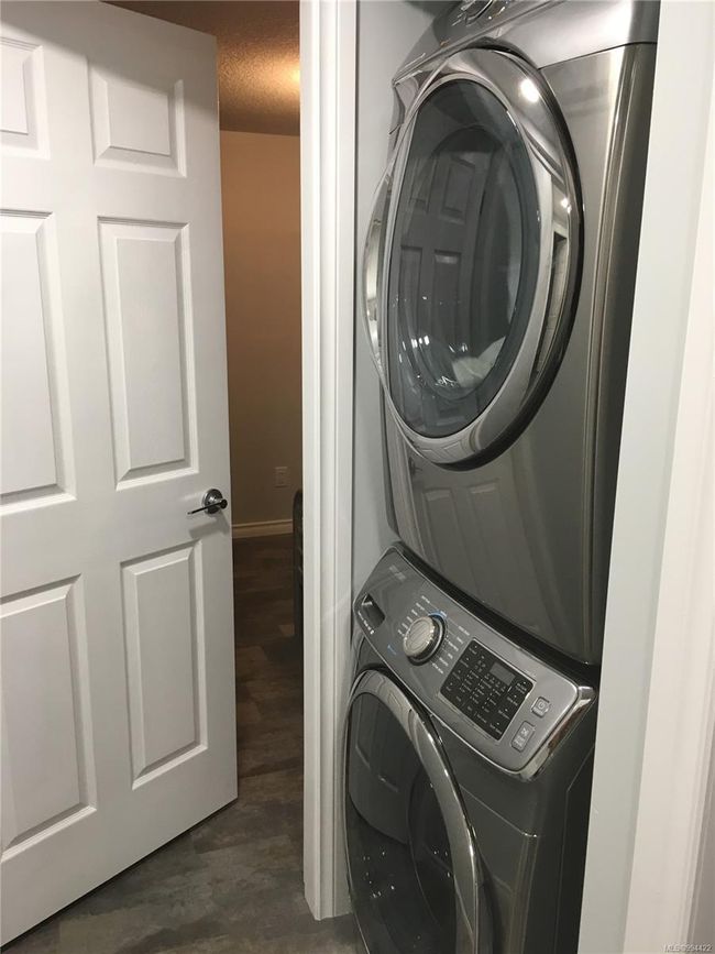 Washroom featuring baseboards, laundry area, dark wood-style floors, stacked washer / drying machine, and a textured ceiling | Image 21