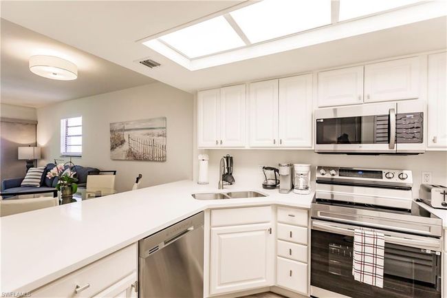 Kitchen with a sink, open floor plan, light countertops, appliances with stainless steel finishes, and visible vents | Image 9