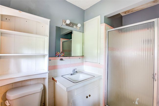 Bathroom featuring toilet, a shower stall, vanity, decorative backsplash, and tile walls | Image 24
