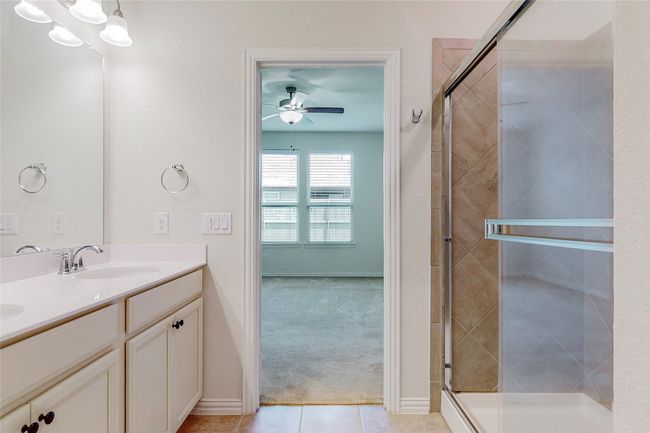 Full bath featuring double vanity, a ceiling fan, a stall shower, tile patterned floors, and baseboards | Image 20