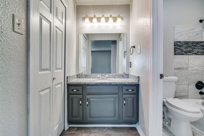 Bathroom with vanity, a textured wall, wood finished floors, a closet, and washtub / shower combination | Image 22