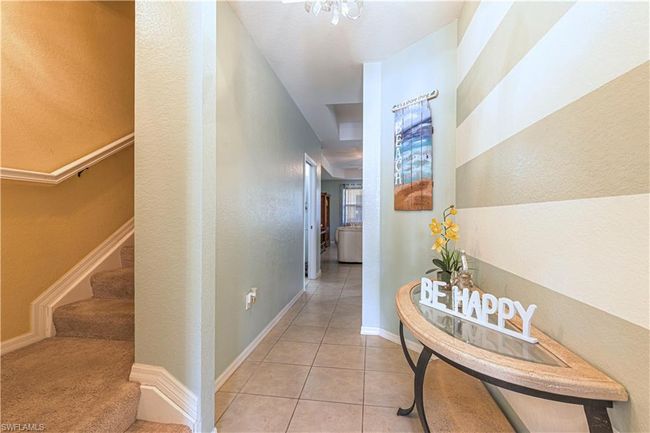 Hallway featuring stairway, light tile patterned floors, baseboards, and a textured wall | Image 11