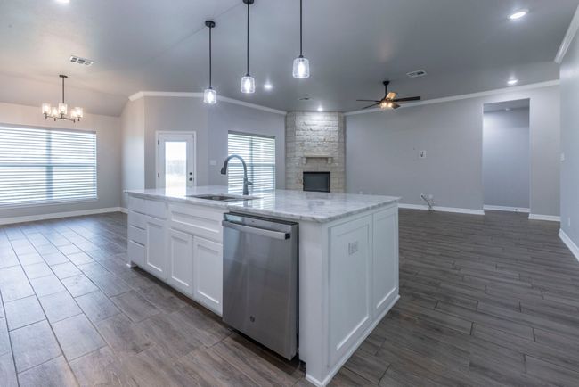 Kitchen featuring dishwasher, a ceiling fan, open floor plan, a fireplace, and crown molding | Image 8