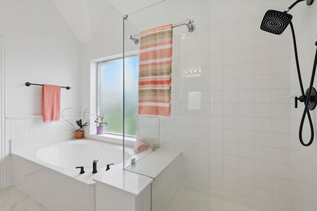 Frameless glass enclosed shower with black fixtures and large, separate garden tub. | Image 20