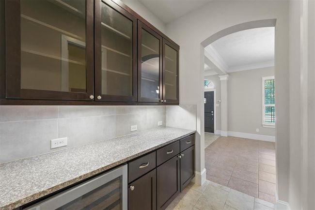 Beautiful butler's pantry with granite countertops, upper glass-front display cabinets, under-cabinet storage, and a built-in wine fridge. Perfectly situated between the kitchen and dining room for effortless entertaining and additional prep space. | Image 6