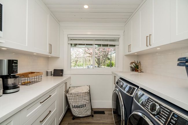 Washroom with dark wood finished floors, recessed lighting, cabinet space, baseboards, and washer and clothes dryer | Image 10