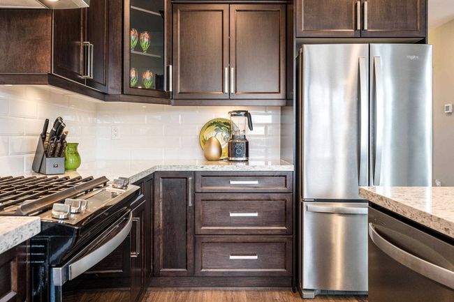 Kitchen featuring dark brown cabinets, appliances with stainless steel finishes, and decorative backsplash | Image 16