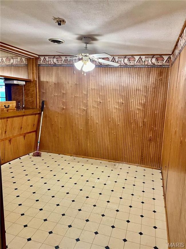 Unfurnished dining area with a textured ceiling, ceiling fan, and wood walls | Image 6