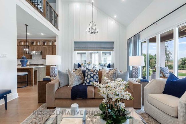 Living room with high vaulted ceiling, a chandelier, light wood-type flooring, and recessed lighting | Image 4