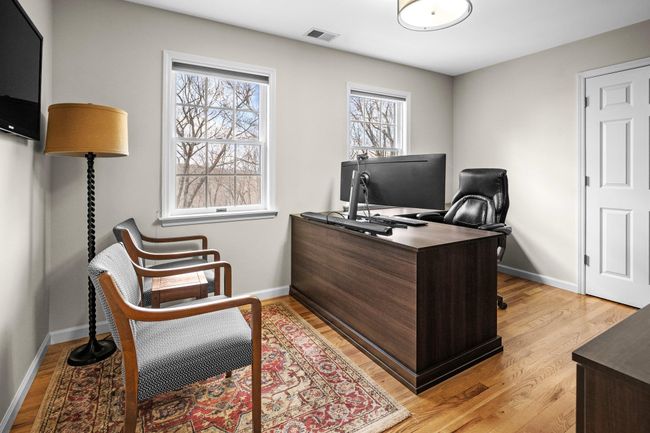 This versatile space, one of five bedrooms, is currently being utilized as a home office—offering a quiet and bright environment with dual windows, hardwood floors, and ample room for productivity. | Image 28