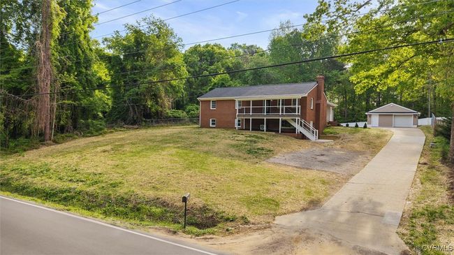 View of front facade featuring a chimney, an outbuilding, a detached garage, a front lawn, and stairs | Image 46