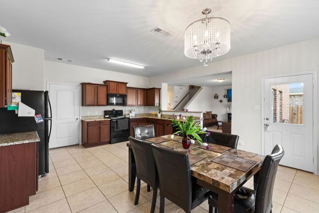 Dining room featuring a chandelier, visible vents, stairs, and light tile patterned flooring | Image 12