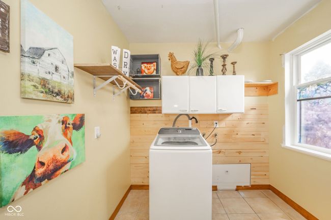 laundry area featuring cabinet space, washer / clothes dryer, baseboards, and light tile patterned floors | Image 33
