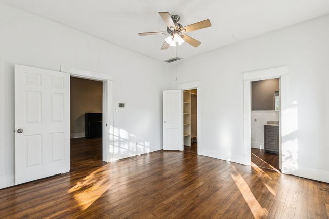 Unfurnished bedroom with wood finished floors, baseboards, a spacious closet, ceiling fan, and a closet | Image 10