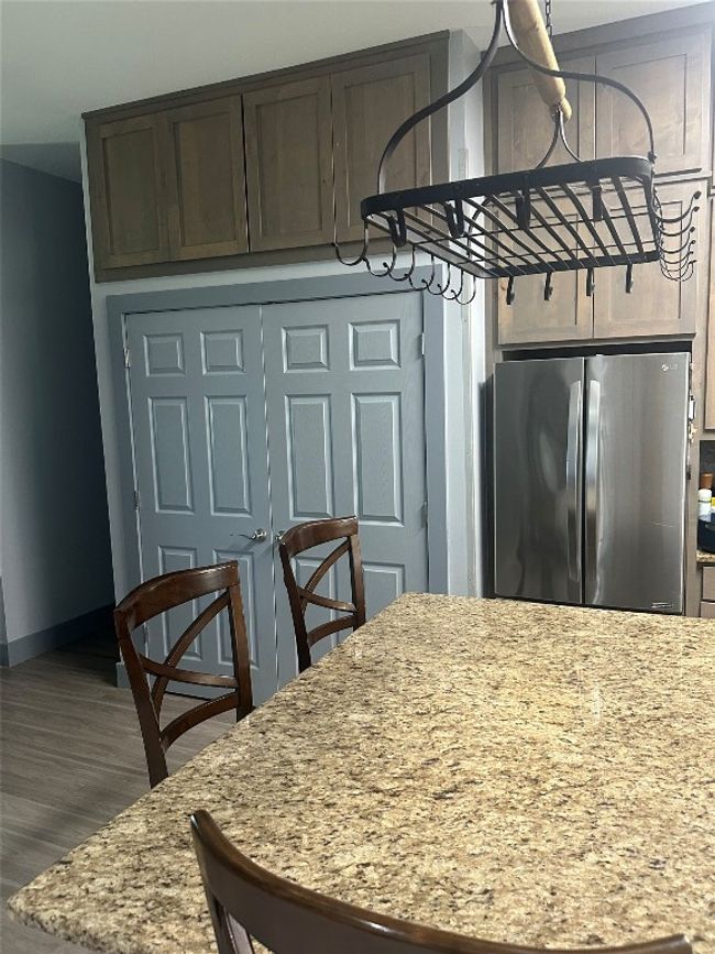 Kitchen featuring freestanding refrigerator, wood finished floors, baseboards, and light stone counters | Image 35