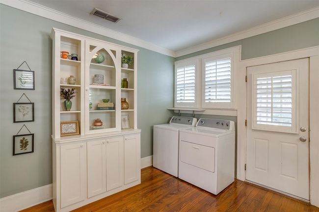 Laundry room with cabinet space, washing machine and dryer, ornamental molding, dark wood-type flooring, and healthy amount of natural light | Image 22