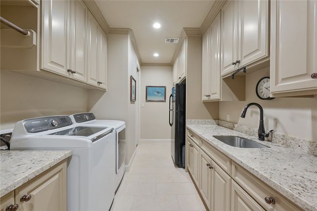 Laundry area featuring separate washer and dryer, baseboards, light tile patterned floors, ornamental molding, and cabinet space | Image 10