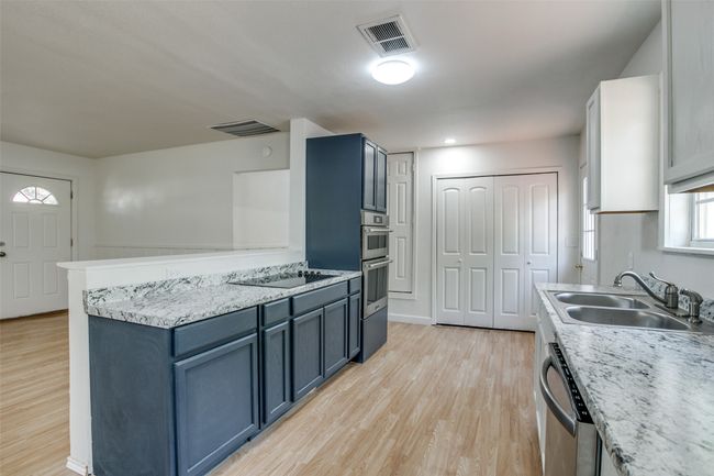 Kitchen with stainless steel dishwasher, light wood-style floors, blue cabinetry, and a peninsula | Image 11