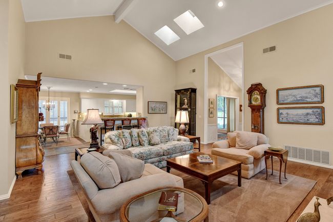 Living room with high vaulted ceiling, wood finished floors, a skylight, baseboards, and beam ceiling | Image 12